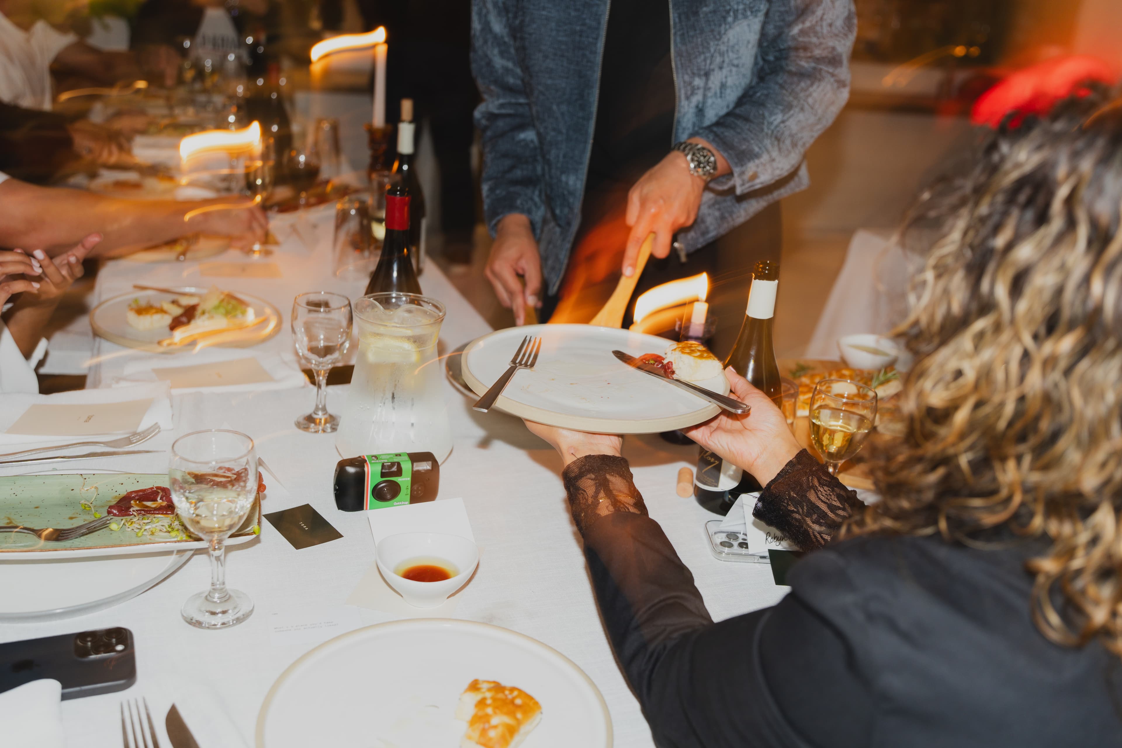 Hands passing a plate across the dinner table