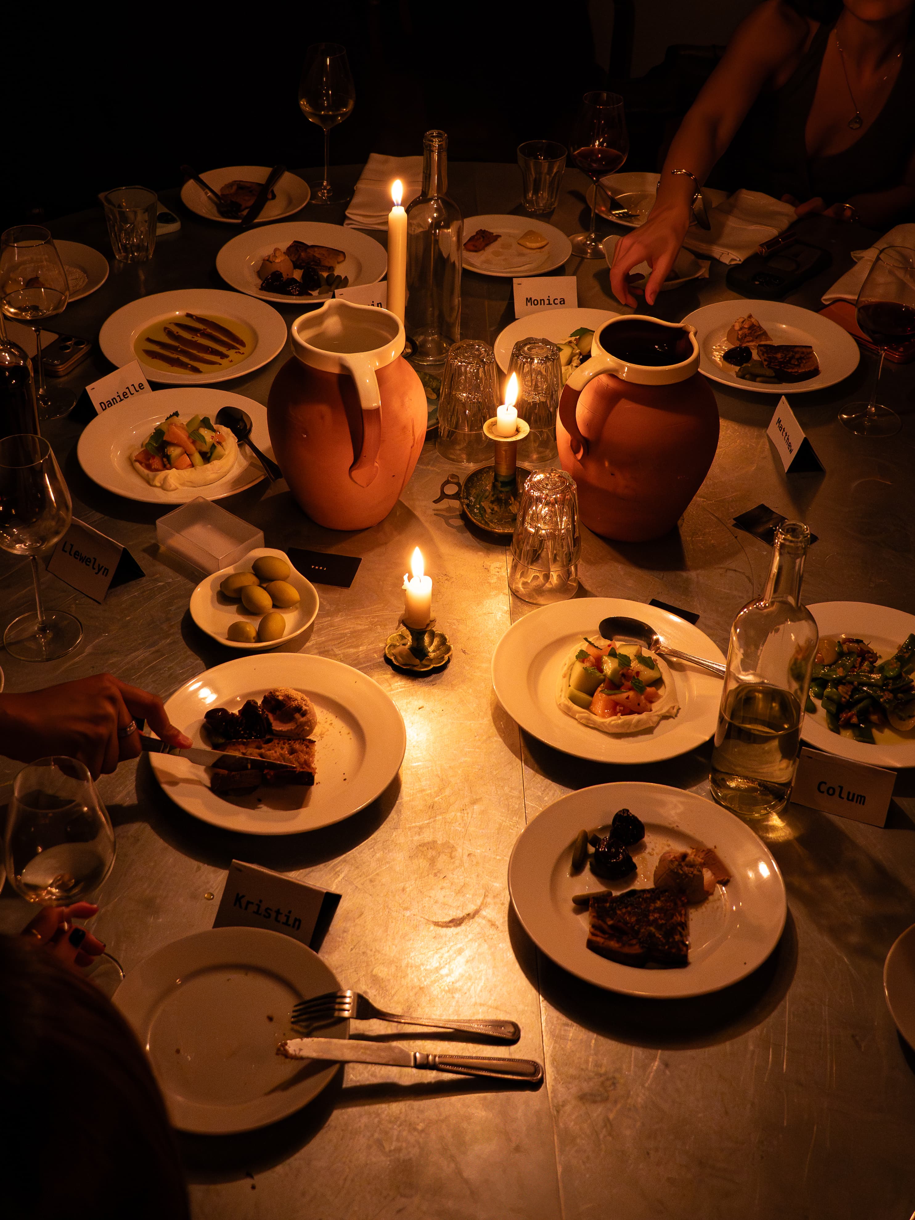 Guests sharing dinner around candlelight and ceramic jugs