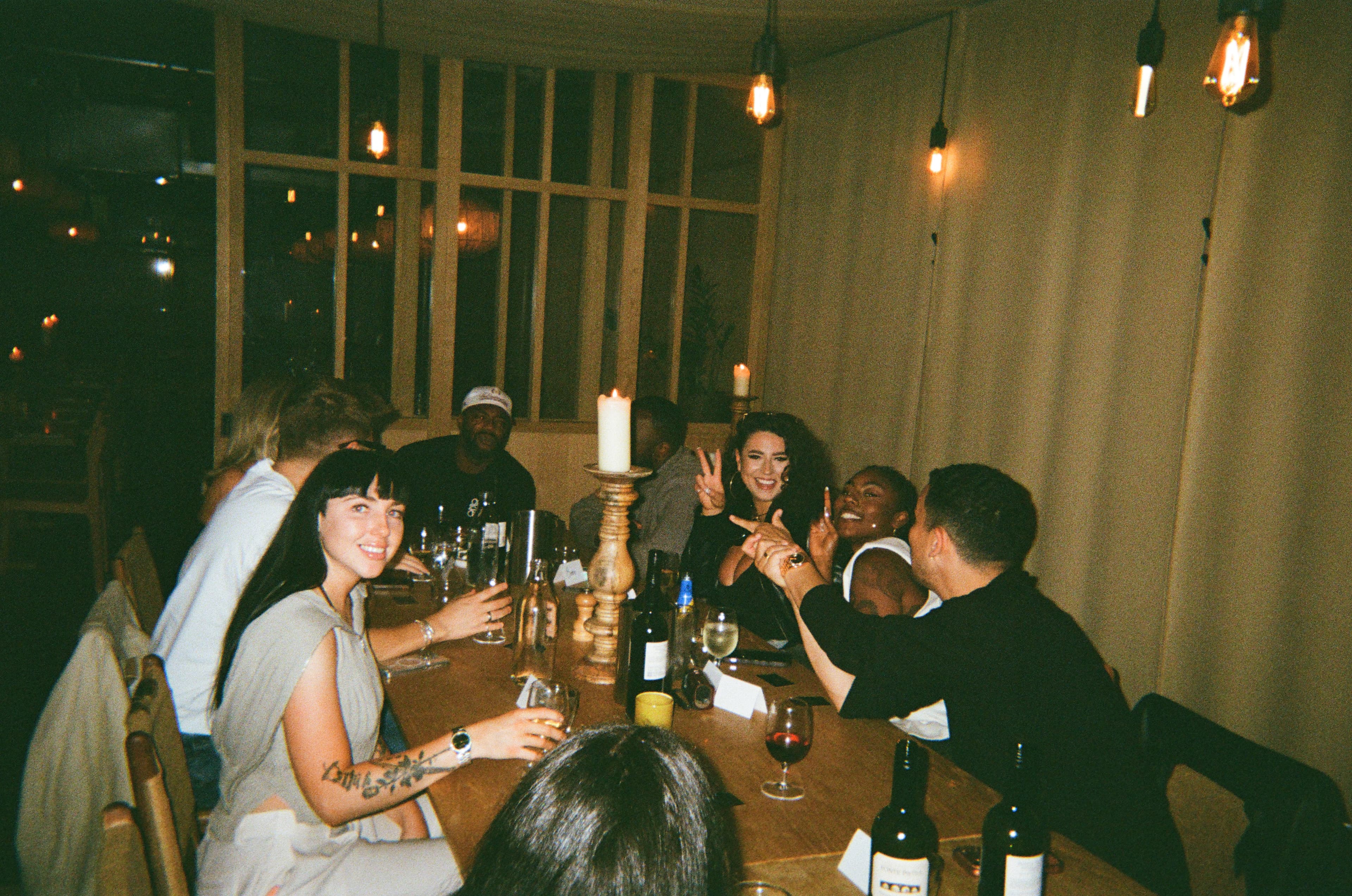 Guests smiling and gesturing across a candlelit table