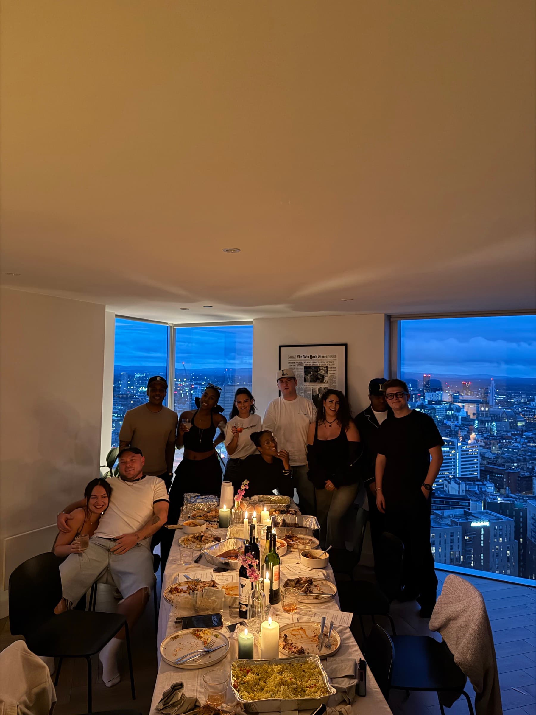 Guests gathered at the end of a long candlelit table high above Manchester, the city at dusk through the windows